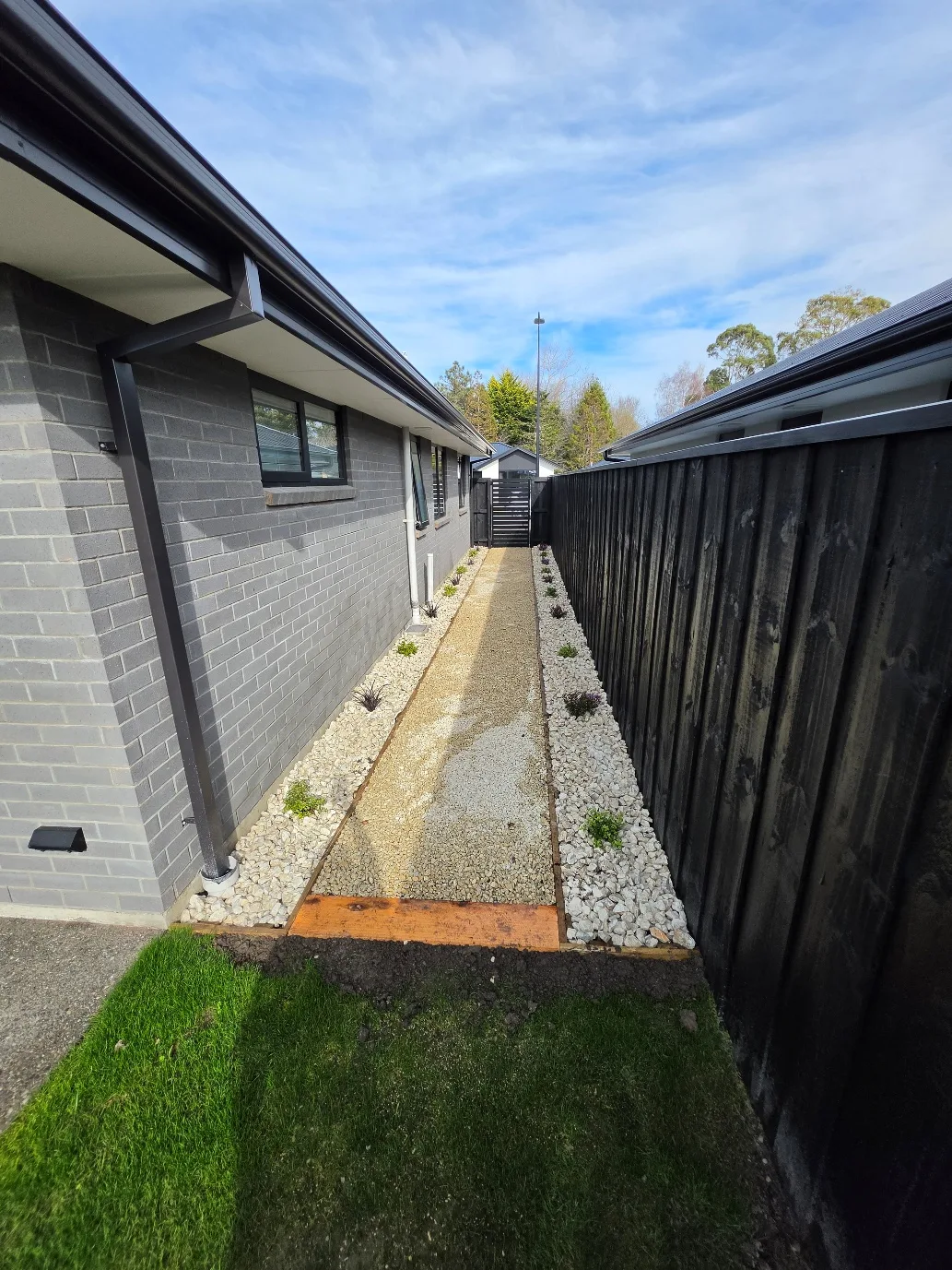 Side yard landscaping with decorative gravel and fencing at 25 Derbridge Street, Christchurch