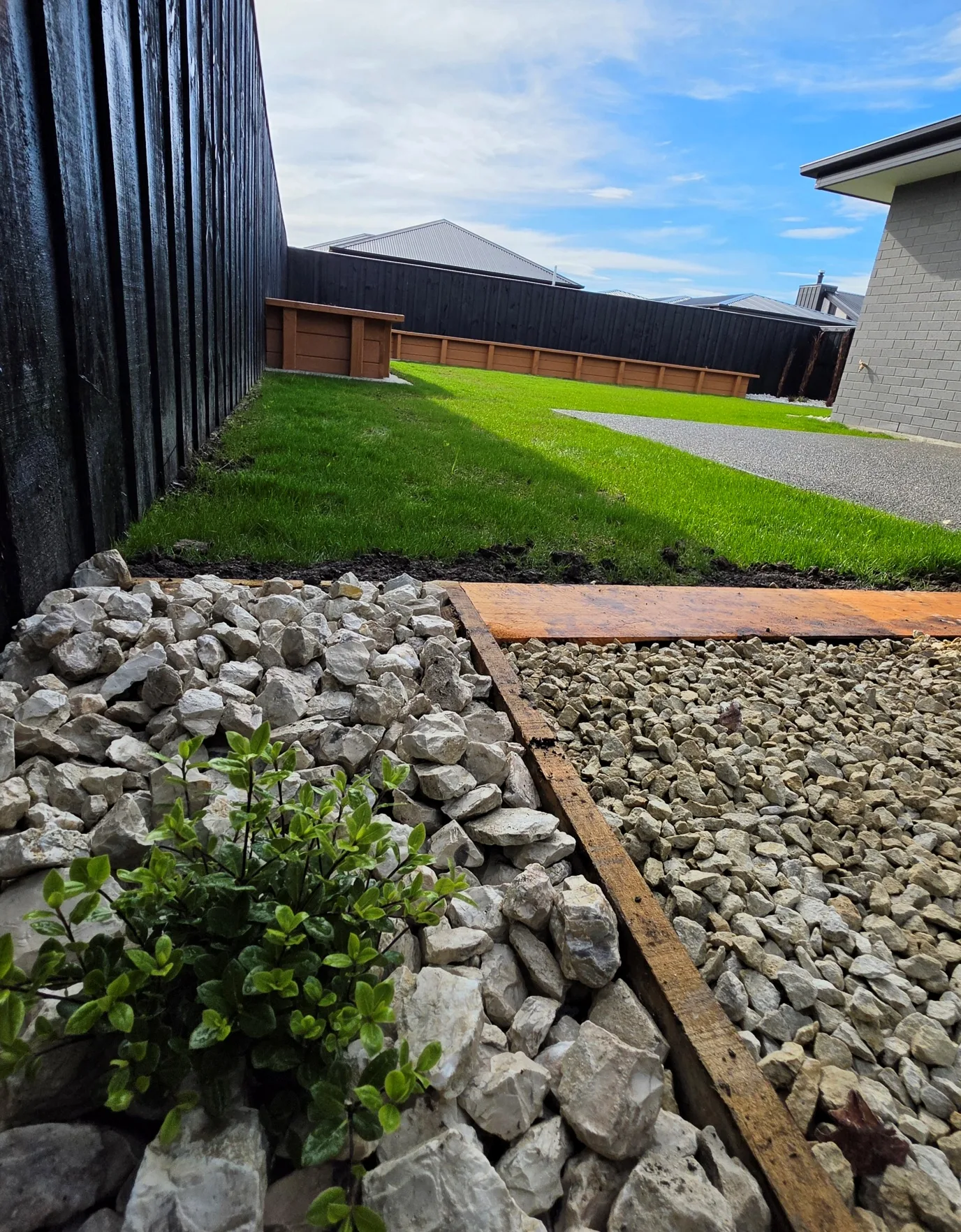 Completed backyard landscaping with fresh lawn, planter beds and black boundary fencing at 25 Derbridge Street, Christchurch